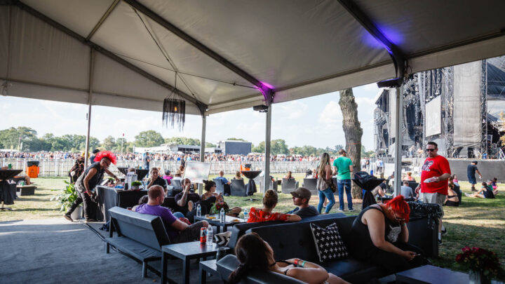 Shaded tent area in the Deluxe VIP lounge with views of Riot Fest stages